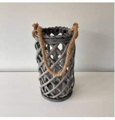 A large grey woven wicker lantern with a chunky rope handle accent and glass insert 