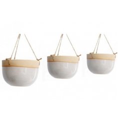 An assorted sized set of hanging ceramic planters, each set with neutral colour tones and a smooth glaze finish 
