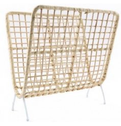 A natural rattan woven magazine rack with added white accents