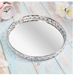  A large round mirrored tray featuring a raised edging with added crystal features 