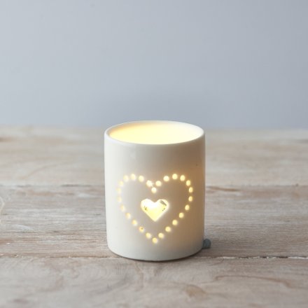  A simplistic white toned ceramic candle pot featuring a pierced heart text decal 