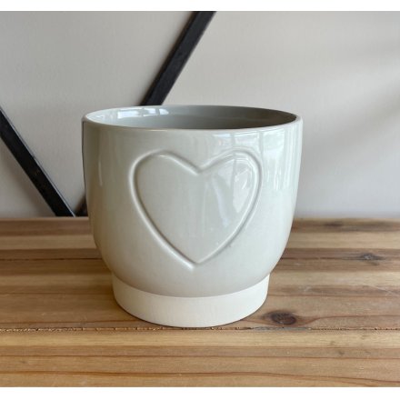 A small ceramic pot featuring a smooth cream finish and subtle embossed heart design 