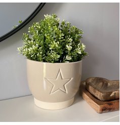 A small ceramic pot featuring a smooth cream finish and subtle embossed star design 