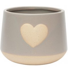 A grey toned ceramic planter featuring a stoneware inspired heart central decal 