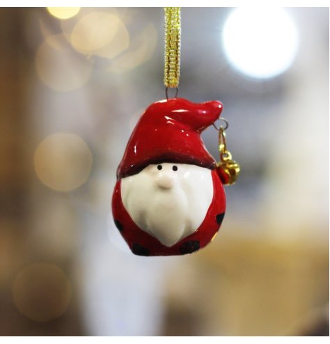 A small hanging ceramic gonk with red tones and a jingling bell finish  