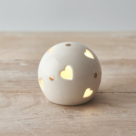A small and simple rounded ceramic ball set with heart cut details and added gold dots 
