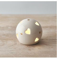 A small and simple rounded ceramic ball set with heart cut details and added gold dots 