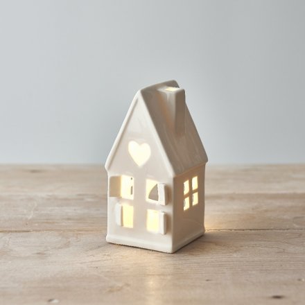  A dainty little ceramic house featuring open windows and a star cut decal to the roof 