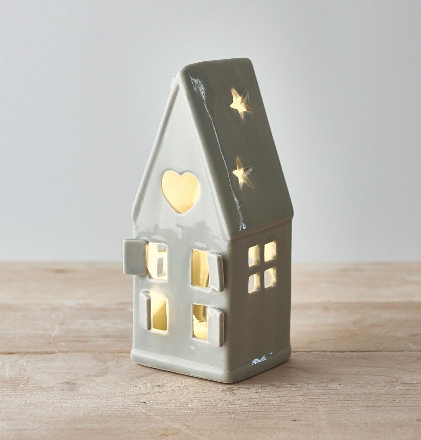  A dainty little ceramic house featuring open windows and a star cut decal to the roof 