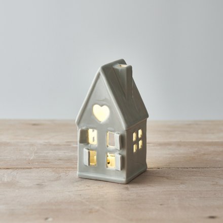 A dainty little ceramic house featuring open windows and a star cut decal to the roof 