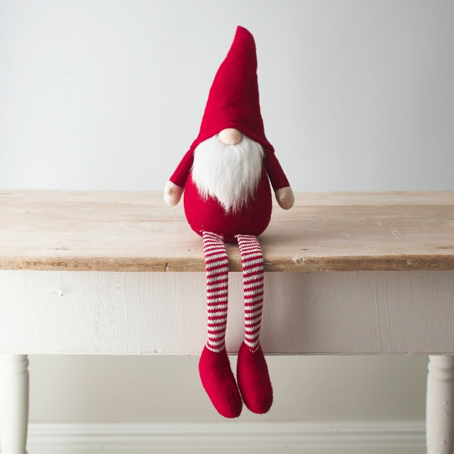   A delightfully festive themed fabric shelf sitting gonk with long dangly legs and a high pointed hat 