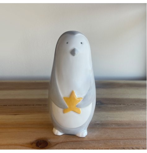 A grey toned ceramic penguin complete with a gold star 