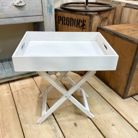  A natural wooden tray table on collapsable legs in a soft distressed white hue 
