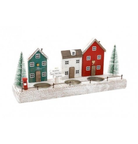 A wooden based village scene tlight holder set with nordic tones and festive decals around it 
