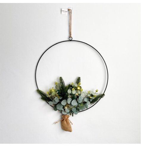 A metal hoop hanging wreath set with a leaf entwined decal and subtle warm glowing led display 