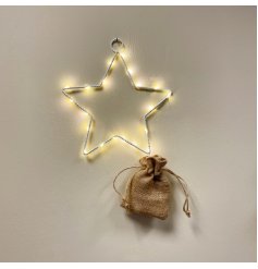 A white metal wire star decoration with warm glowing LED lights and a hessian battery bag 