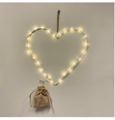 A white metal wire heart decoration with warm glowing LED lights and a hessian battery bag 