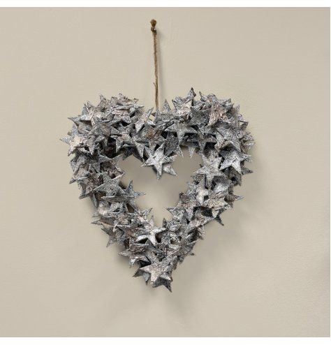 A rustic heart shaped wreath covered with silver toned birch bark stars and hung from a jute string 