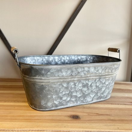   An aged looking metal planter featuring a washed look and wooden handles for feature 