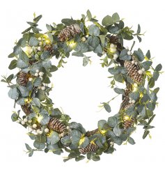 A stunning round wreath built up of greenery foliage, pinecones, berries and warm glowing LED lights 
