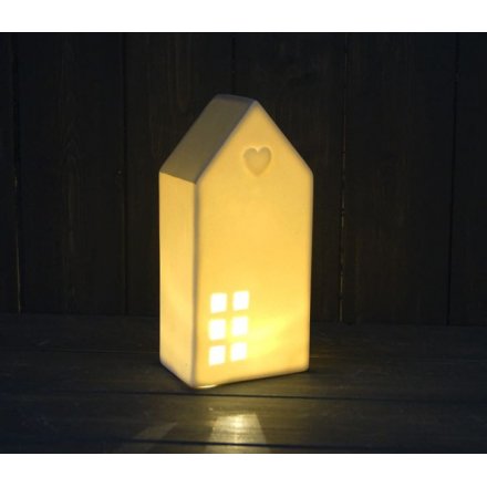 A small ceramic house with white tones and a soft grey roof complete with a warm glowing LED central light 