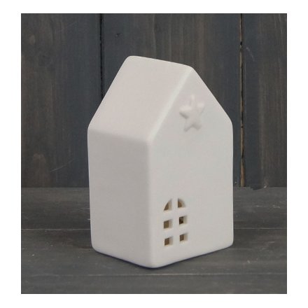 A small ceramic house with only white tones, complete with a warm glowing LED central light and star embossment 