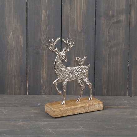 A festive themed metal stag ornament on a natural wood base 