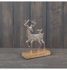A festive themed metal stag ornament on a natural wood base 