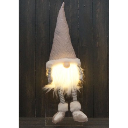 A plush gonk shelf sitter with neutral cream tones and warm glowing LED lights in his beard