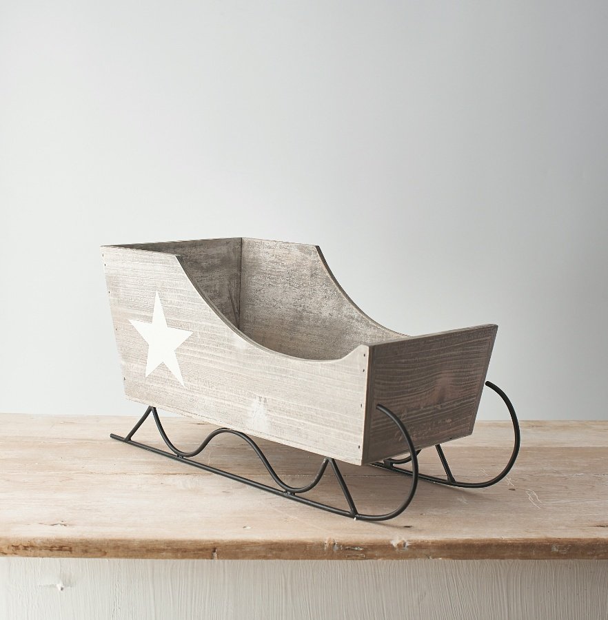 A large decorative wooden sleigh with a simple white star to feature