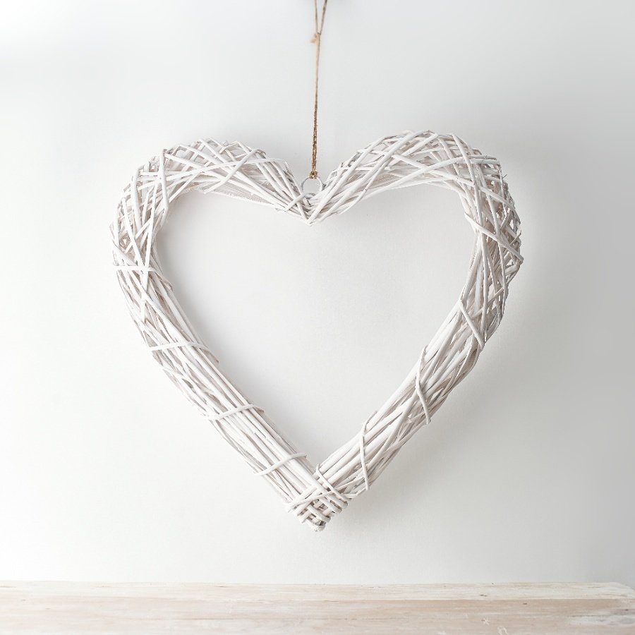 A chic white woven wicker heart with a jute string for hanging 