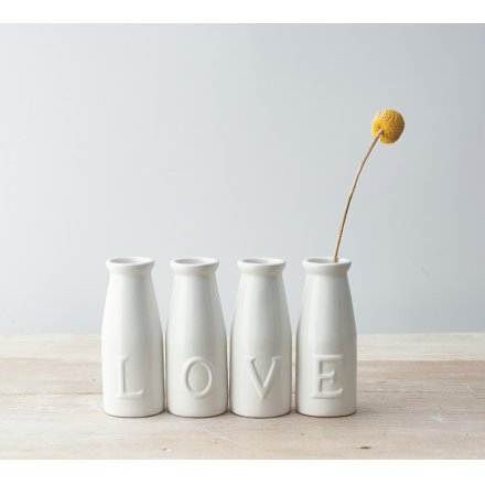 A set of simple white toned ceramic milk bottles, each embossed with a letter that spells out LOVE 