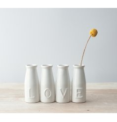 A set of simple white toned ceramic milk bottles, each embossed with a letter that spells out LOVE 