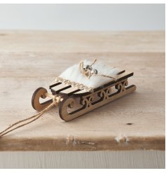  A wooden sledge hanging decoration with added faux fur trims and a jute bow with bell 