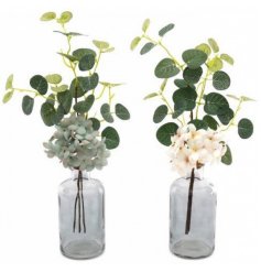 A sleek mix of clear glass vases, each filled with beautiful artificial flowers and eucalyptus leaves 