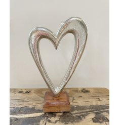 A Large Metal Heart Ornament on a Wooden Block