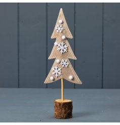 A chic natural Christmas tree stood upon a wooden base. Decorated with white pom poms and snowflakes.