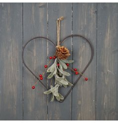 A traditional heart shaped metal wreath decorated with red festive berries, mistletoe and a pinecone.