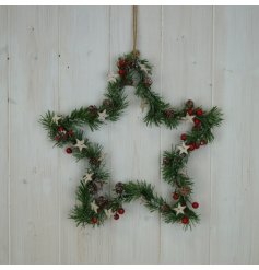 A traditional foliage star shaped wreath decorated with festive red berries and wooden stars. 