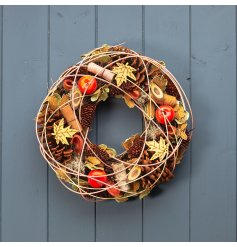 Autumn table centrepiece or wreath with faux fruit, pine cones and wooden leaves.