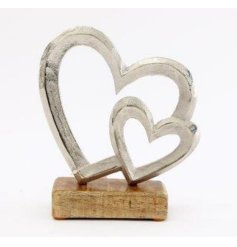 A rustic interior accessory featuring 2 distressed metal hearts on a natural wooden base.