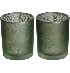 An assortment of 2 frosted glass candle holders each with a unique floral pattern. 