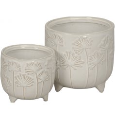 A set of two cream planters, each with a pretty raised floral design and feet.