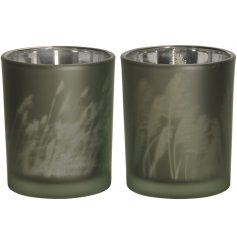 An assortment of 2 forest green glass candle holders, each with a frosted finish and beautiful grass print.