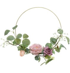 A wire wreath wrapped with artificial flowers and foliage in pretty pink hues.