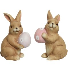 An assortment of 2 charming terracotta bunny ornaments, each holding a pink or lilac floral decorated egg. 