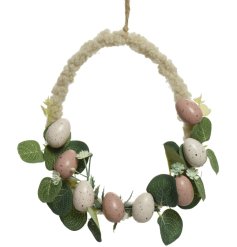 An egg shaped wreath decorated with an array of pastel coloured eggs and artificial foliage. 