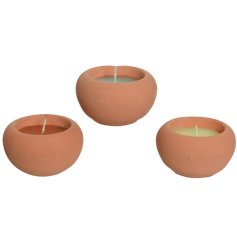 An assortment of 3 colourful citronella candles set within rustic terracotta pots.