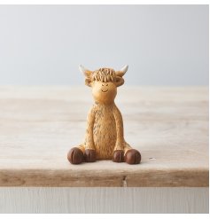 A charming sitting highland cow ornament with a cute smiling face .