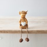 A charming highland cow shelf sitting ornament with a cute white heart detail.